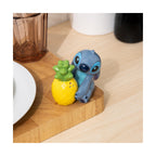 Ceramic Stitch from Lilo & Stitch hugging a yellow pineapple salt shaker on a wooden surface.