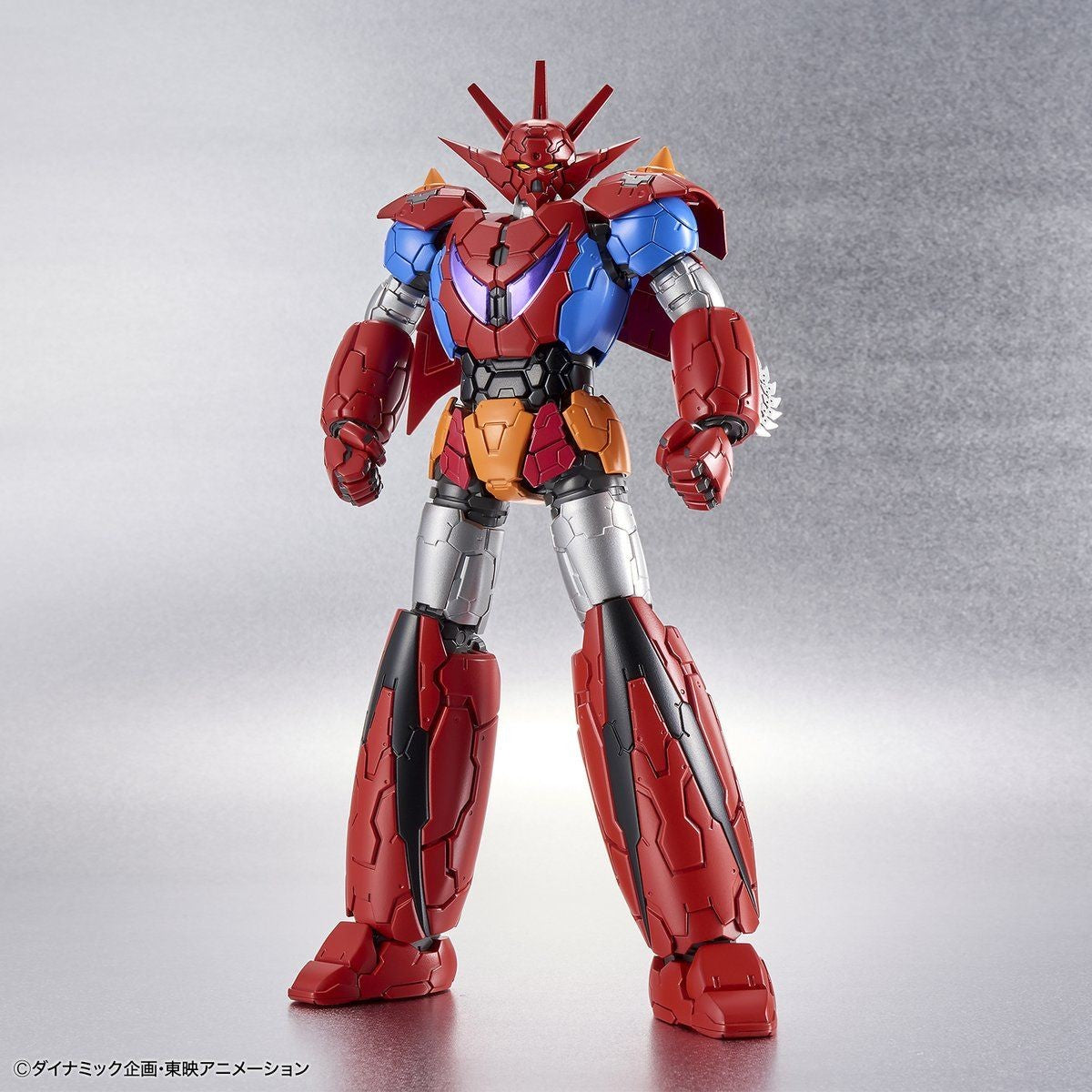 Getter Robo action figure in red, blue, and orange with a spiked head, standing against a metallic silver background.