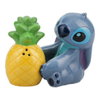 Ceramic salt and pepper shakers shaped like Stitch from Lilo & Stitch sitting next to a bright yellow pineapple.