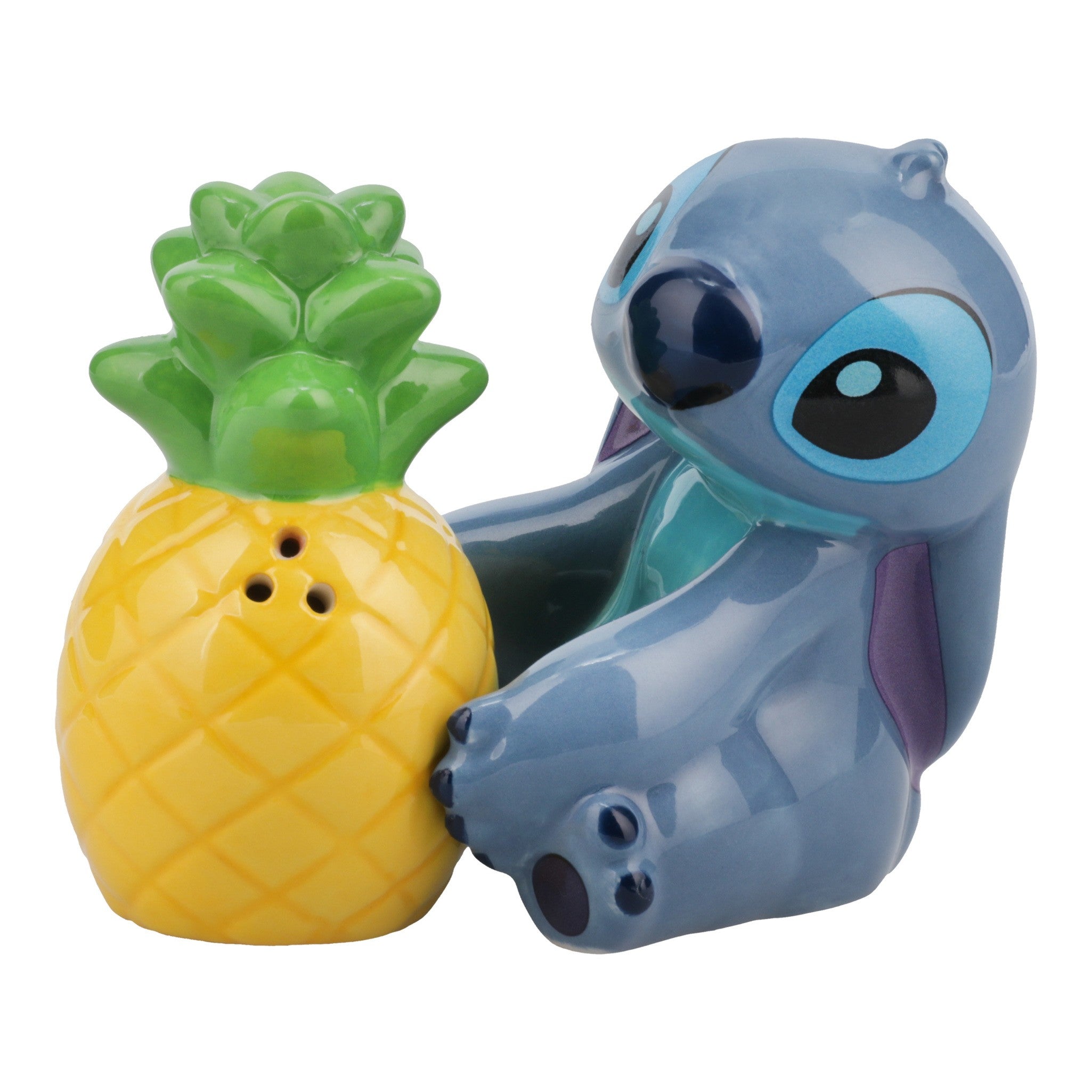 Ceramic salt and pepper shakers shaped like Stitch from Lilo & Stitch sitting next to a bright yellow pineapple.