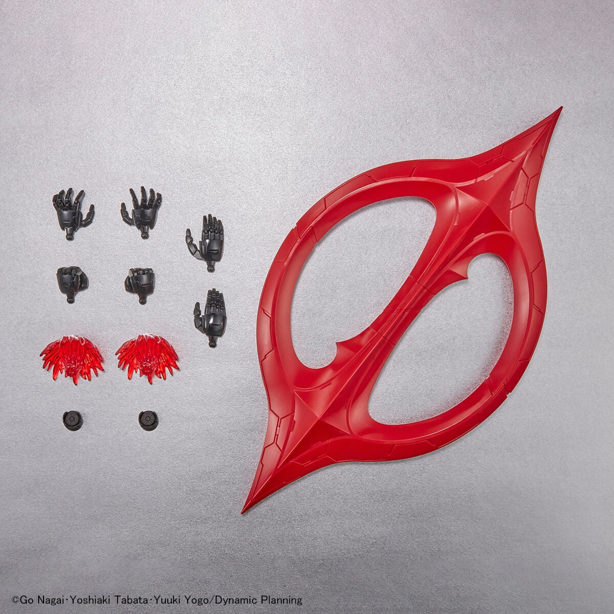 Action figure accessory set: a large red crescent blade, black hand parts, spiky red energy effects, and small joints.