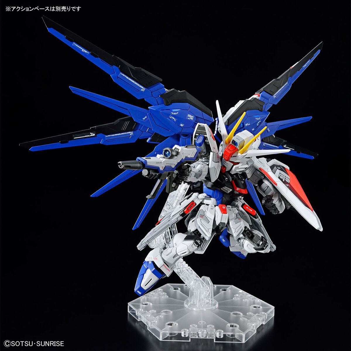 Model kit Bandai MGSD Freedom Gundam in posa dinamica su base espositiva, dettaglio del robot bianco e blu.