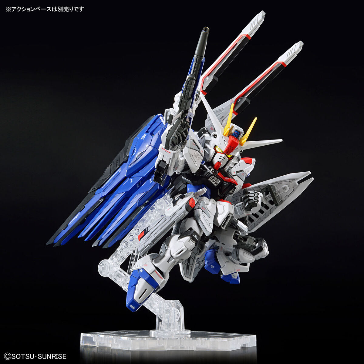 Model kit Bandai MGSD Freedom Gundam in posa dinamica su base espositiva, dettaglio del robot bianco e blu.