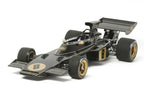 Modellino Tamiya Team Lotus Type 72D 1972 scala 1:12, auto da corsa nera e oro su sfondo bianco.