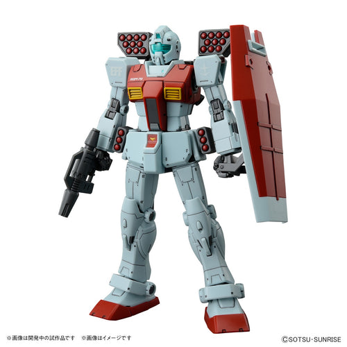 Model kit Bandai HG 1/144 GM con missile pod, fucile e scudo, in posa frontale su sfondo bianco.