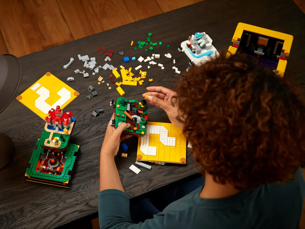 Persona che costruisce il set LEGO Super Mario 71395 Blocco Punto Interrogativo con livelli ispirati a Super Mario 64.