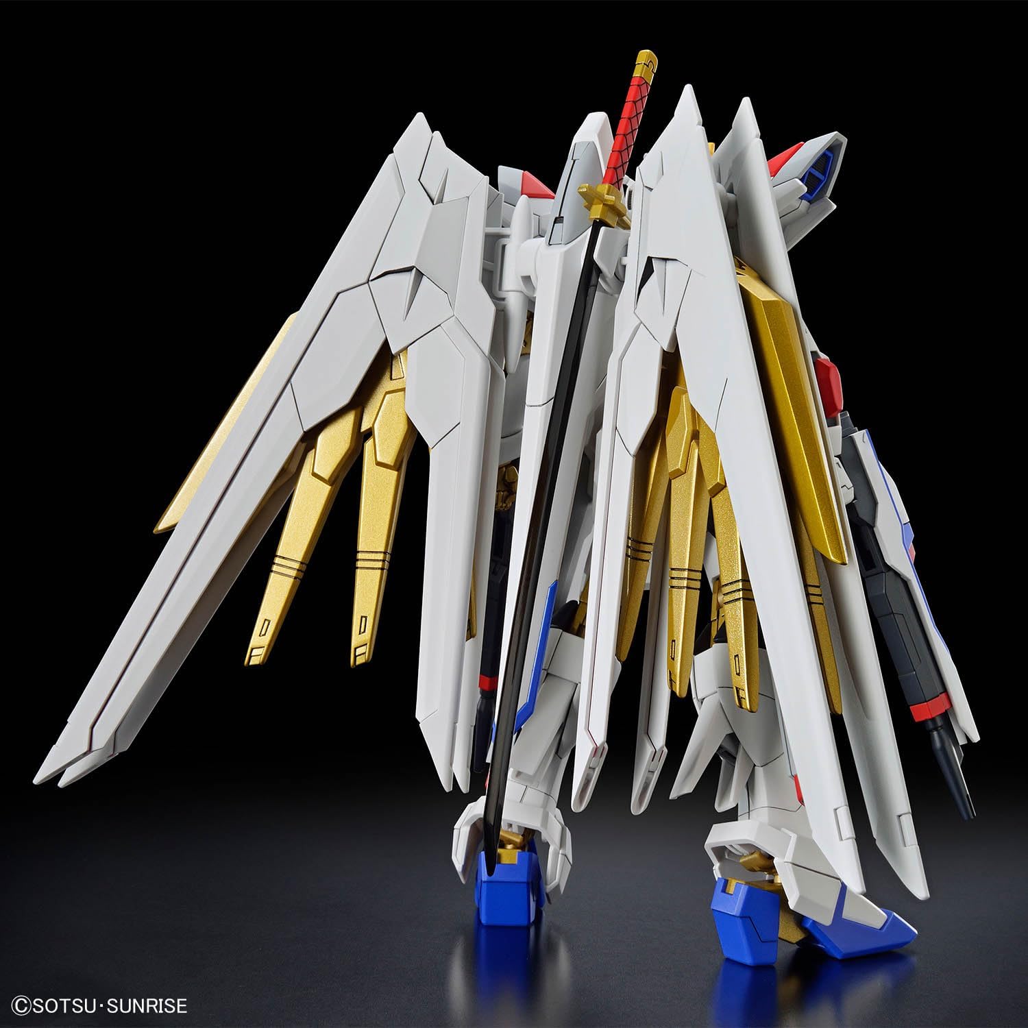 Vista posteriore del model kit Bandai 1/144 HG Mighty Strike Freedom Gundam con ali bianche e dorate.