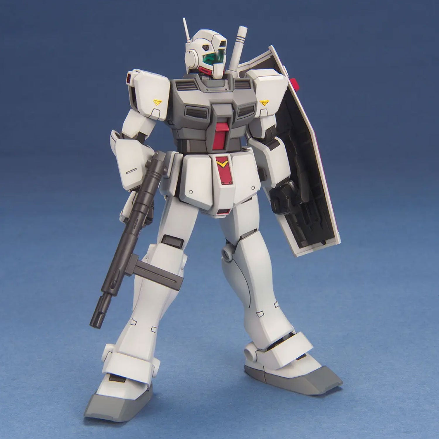 White and gray Gundam model kit standing with a shield and beam rifle against a blue background.
