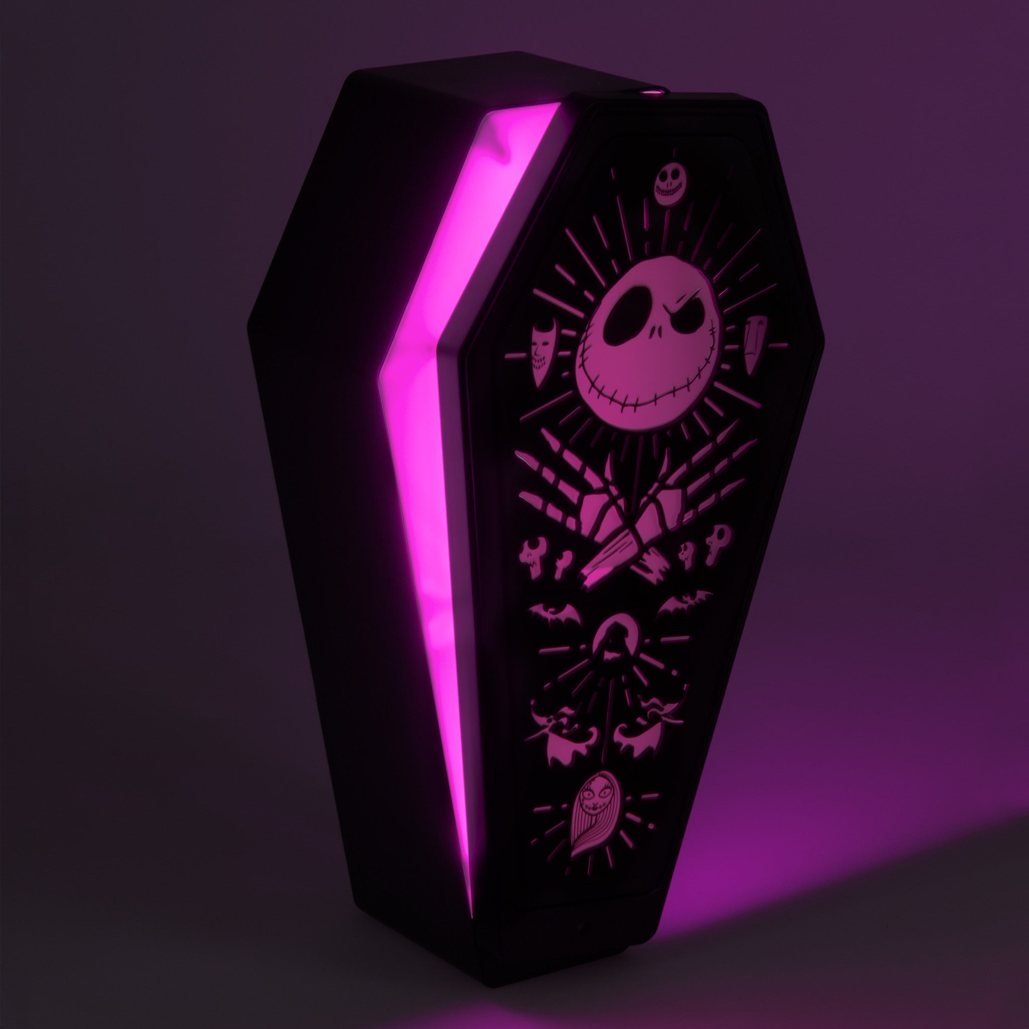 Black coffin-shaped lamp featuring Nightmare Before Christmas graphics, illuminated with a vibrant purple glow.