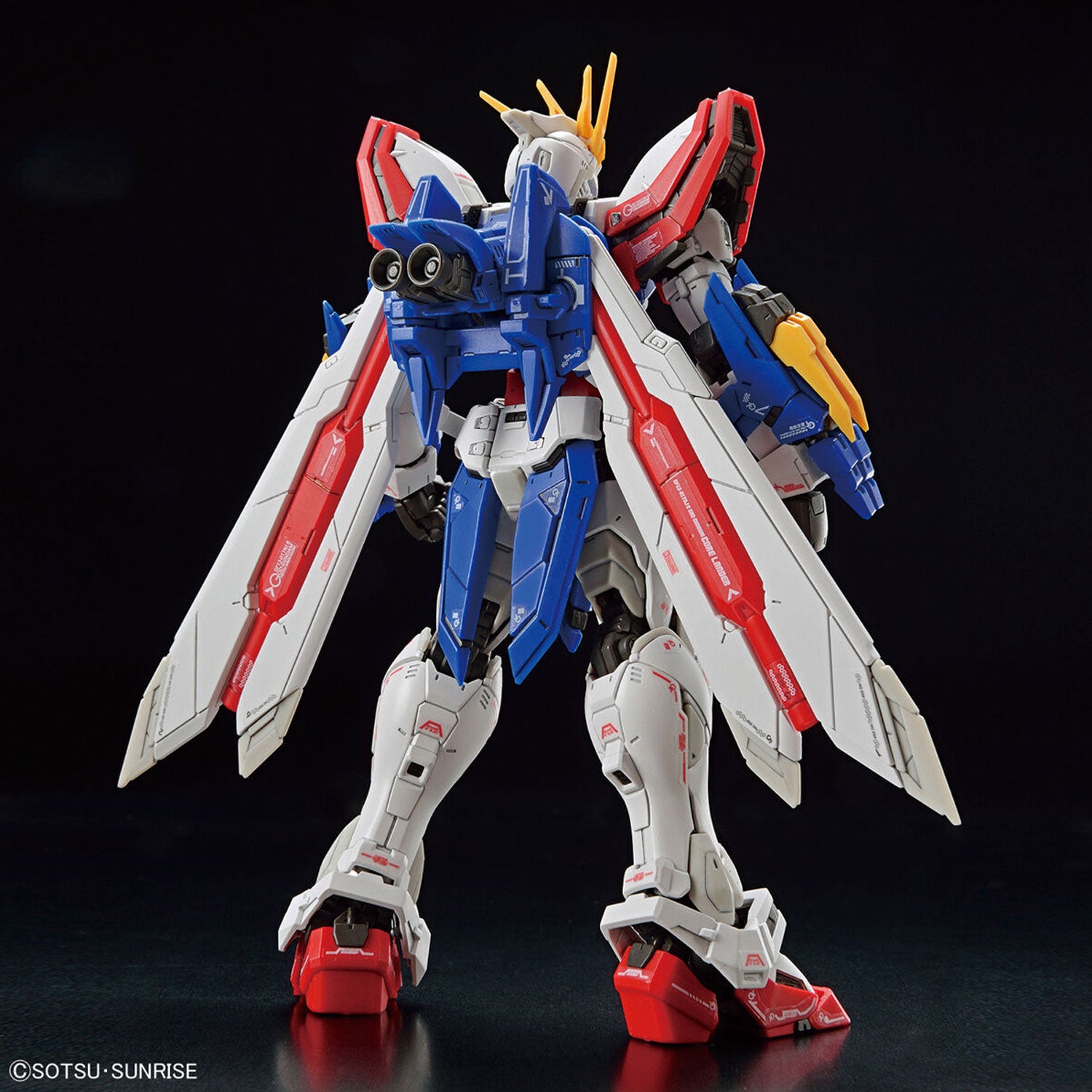 Back view of a red, white, and blue Gundam model kit with large wing-like thrusters on a black background.