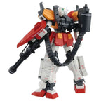 Gundam model kit viewed from behind, featuring white, red, and orange armor with a black gatling gun and ammo belt.