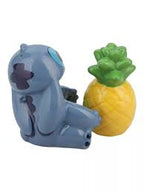 Blue Stitch figurine sitting next to a bright yellow pineapple with green leaves, glossy cartoon-style design.