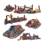 Painted tabletop wargaming terrain: scrap metal barricades, walls, and debris in weathered red, orange, and metallic tones.