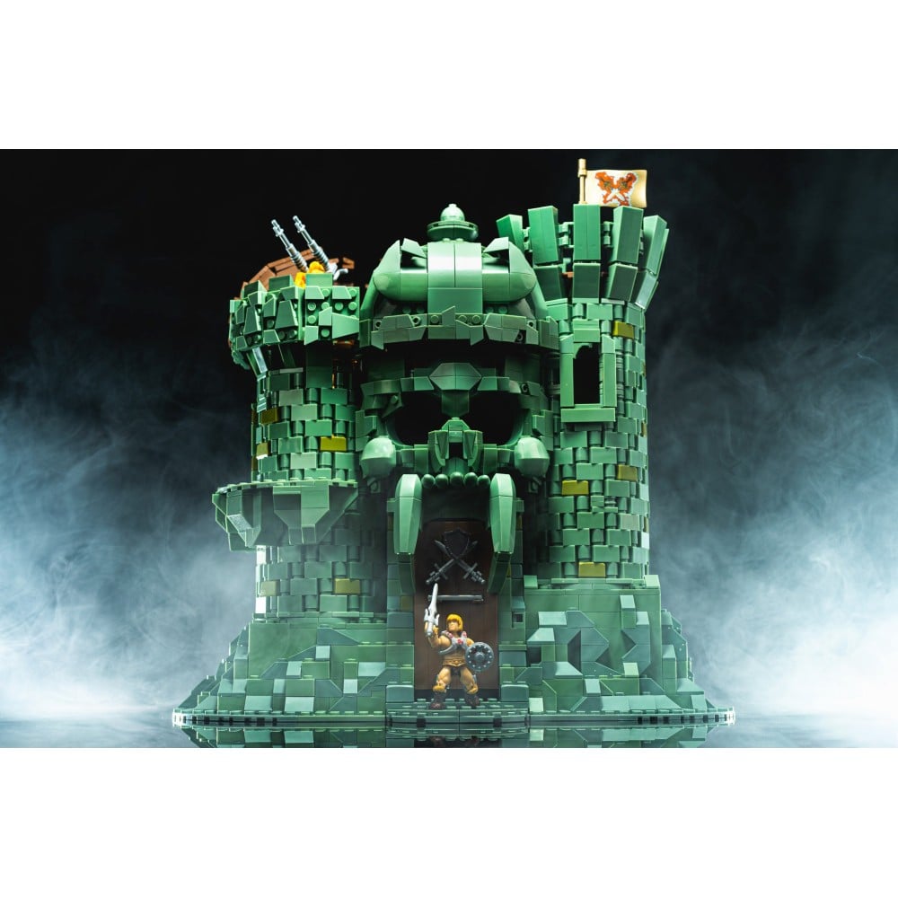 Set costruzioni Mega Construx Castello di Grayskull con action figure di He-Man in primo piano su sfondo nebbioso.